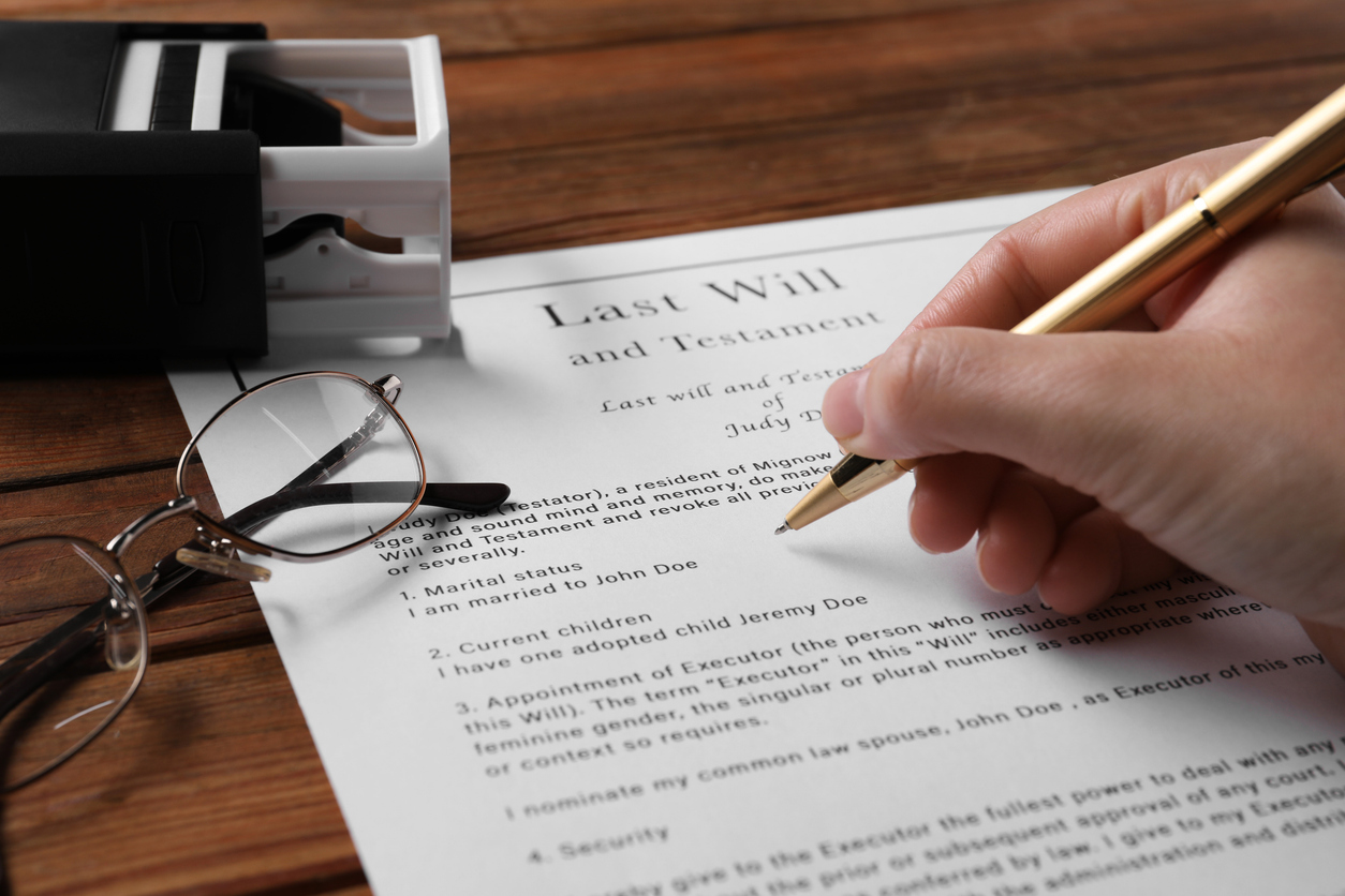 Woman signing Last Will and Testament at wooden table, closeup Supporting your family’s financial future